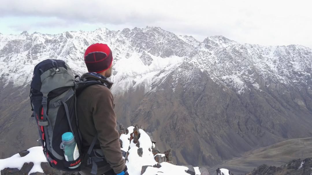 پرتره مرد اسکی سوار ایرانی در حال نگاه به رشته کوه برفی واقع در پیست اسکی رودبارک در مازندران ایران