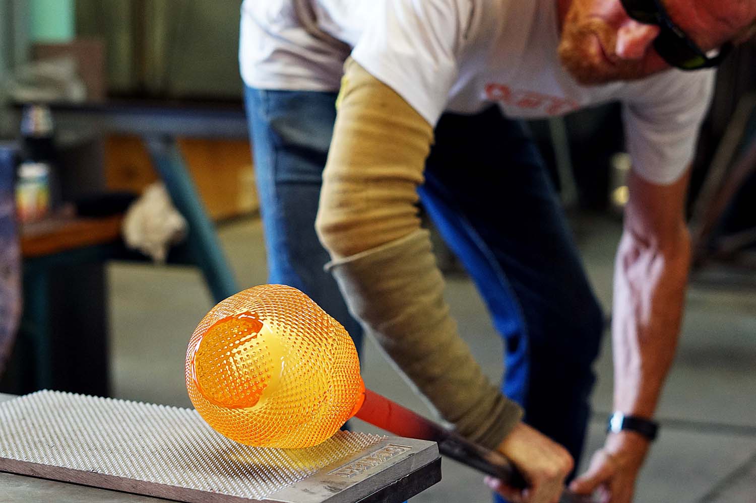 یک مرد شیشه گر درحال ایجاد الگویی از فرورفتگی ها به شیشه مذاب