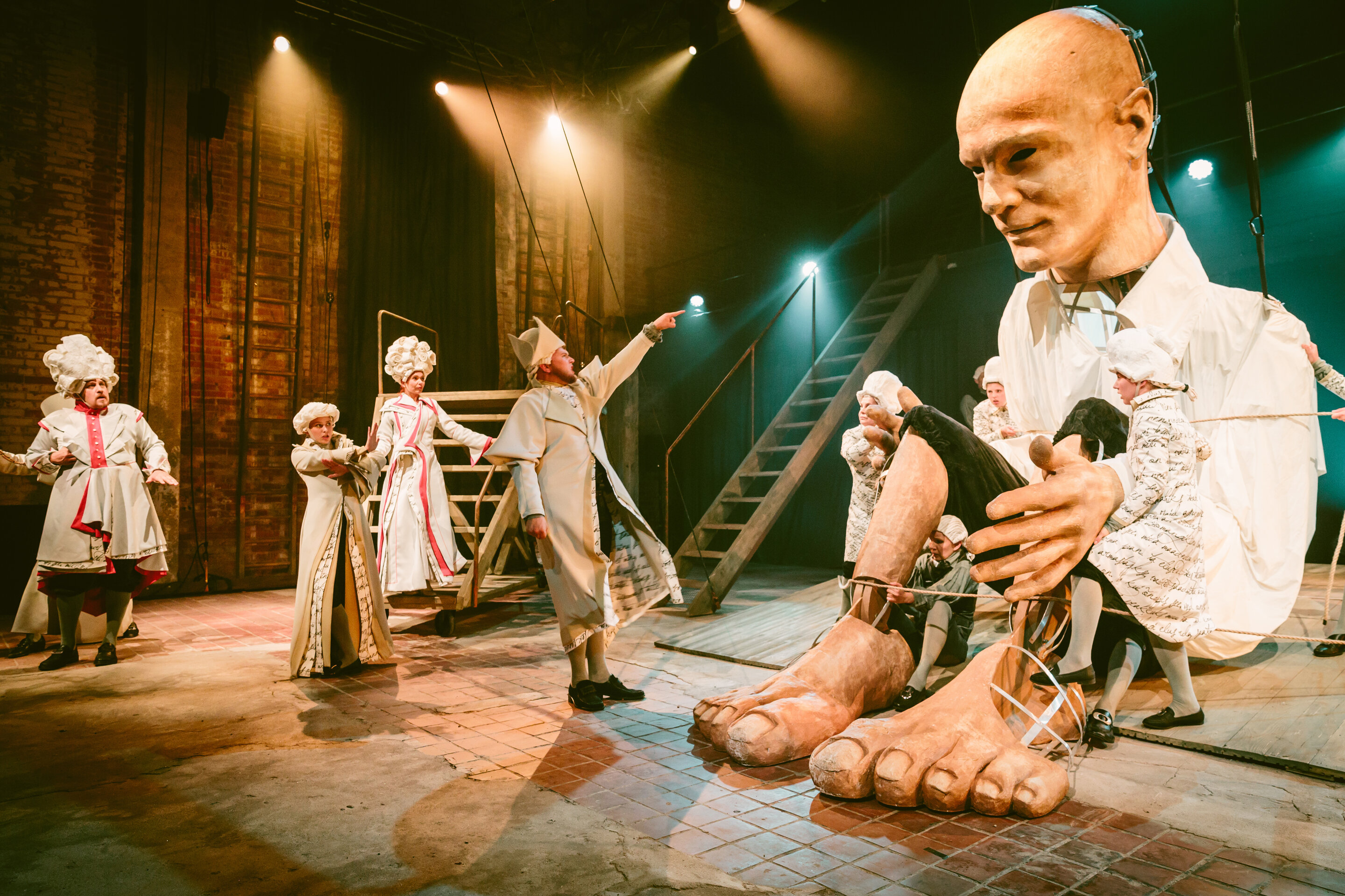 یک صحنه تئاتر عروسکی همراه با بازیگران و هنرمندان عروسک گردان که یک عروسک چوبی بزرگ را به نمایش در می‌آوردند